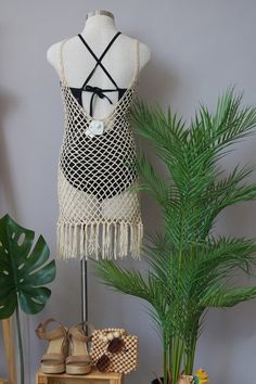 a mannequin wearing a white and black halter top next to a potted plant