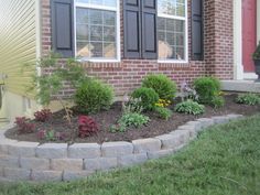 a flower bed in front of a brick house