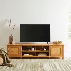 a flat screen tv sitting on top of a wooden entertainment center in a living room