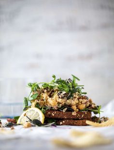 a stack of food sitting on top of a table next to chips and lemon wedges