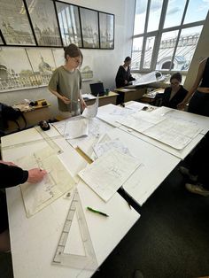 people working on architectural drawings in an office