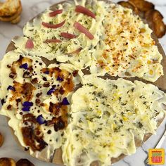 four different types of pizza on a wooden board next to some breads and other food items