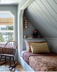 a rocking chair in the corner of a bedroom next to a bed with pillows on it