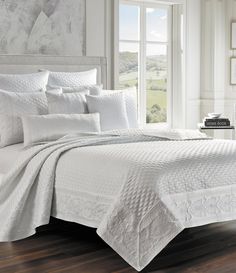 a bed with white sheets and pillows in a room