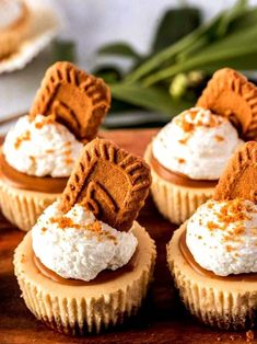 small cupcakes with whipped cream and cookies on top are sitting on a cutting board