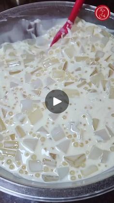 a pan filled with white liquid sitting on top of a stove next to a red spatula