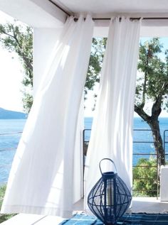 a blue lantern sitting on top of a rug in front of a white curtained window