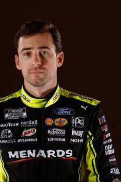 a man in a black and yellow racing suit looking at the camera with serious eyes