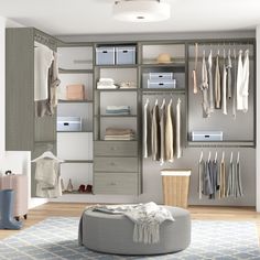 an organized closet with clothes, shoes and other items in the room that includes a round ottoman