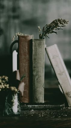 two books are sitting next to each other on a table with flowers in vases