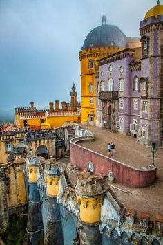 an aerial view of some old buildings with yellow and purple paint on the roof tops