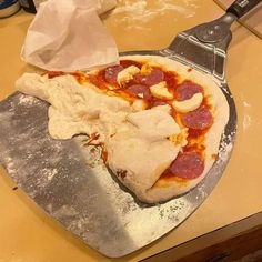 a pizza sitting on top of a pan covered in cheese and pepperoni next to a spatula