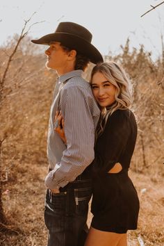 a man in a cowboy hat is hugging a woman's back while she stands next to him