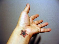 a person's hand with a small star tattoo on the middle of their arm