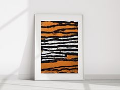 an orange and black abstract painting hangs on the wall next to a white framed art print