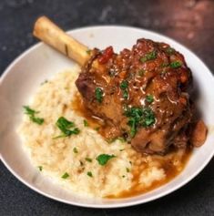 a white plate topped with rice and meat covered in gravy on top of a table