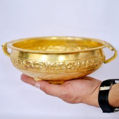 a person holding a golden bowl in their hand