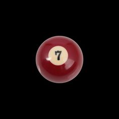 a red pool ball with the number seven on it's side in front of a black background