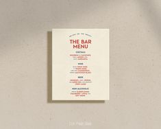 the bar menu is displayed on a white tablecloth against a beige wall with a black and red design