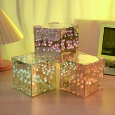 four cubes sitting on top of a wooden table next to a laptop and lamp