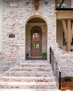 a brick house with an arched door and wrought iron railings on the front steps