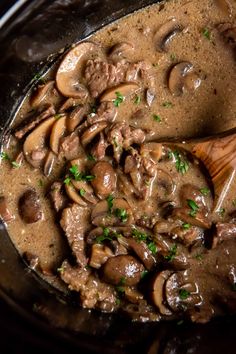 mushrooms are being cooked in a skillet with a wooden spoon