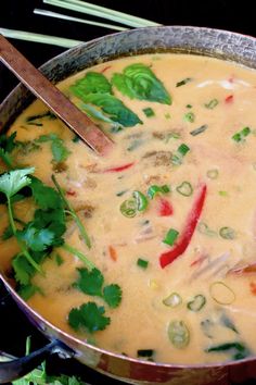 a pot filled with soup next to chopsticks and cilantro