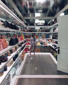 a woman is standing in the middle of a store filled with purses