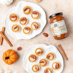 two white plates with mini pumpkin pies and a jar of maple syrup on the side