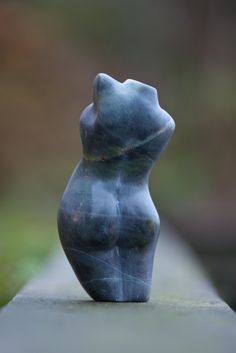 a small gray statue sitting on top of a cement slab