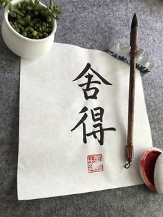 a piece of paper with writing on it next to a potted plant and chopstick