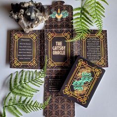 This unique and stunning card deck features actual text from F. Scott Fitzgerald's The Great Gatsby.  Each card includes a snippet of text from the novel, paired with period-style graphic art that enhances the card's meaning and reflects the 1920s Art Deco theme. The card box is designed with a black and gold Art Deco pattern, adorned with images of champagne and palm leaves. The back of the cards also features gold Art Deco designs and palms, tying the theme together beautifully. This 36-card o Black And Gold Art Deco, Gold Art Deco Pattern, Black And Gold Art, Deck Features, Art Deco Theme, Deco Pattern, American Literature, Art Deco Pattern, 1920s Art