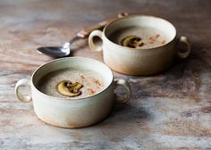 two mugs filled with food sitting on top of a table next to spoons