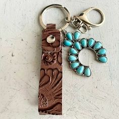 a keychain with a turquoise bead on it next to a brown leather case