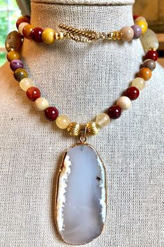 "Stunning Australian mookaite jasper necklace in rich, earth toned colors for fall. Absolutely gorgeous! -  Handmade and one-of-a-kind. -  Large agate druzy with 24K gold electroplate.  Measures 2-1/4\" x 1-1/4\". -  Stunning color combination of Australian mookaite jasper and yellow jade. -  Two hand-drilled, vintage African agates surround the pendant. Measuring about 1\". -  Gold plated spacer beads, crimps, crimp covers, and toggle clasp.  -  Necklace measures 22\" in length. -  Beautifully packaged for gift giving. -  Ships by U.S. Postal Service in 1-3 business days. -  More jewelry: https://www.etsy.com/shop/EbbTideArts?ref=seller-platform-mcnav&section_id=18846708 Thanks for visiting Ebb Tide Arts! ️" Earthy Style Agate Necklace, Multicolor Jasper Spiritual Necklace, Adjustable Multicolor Jasper Necklaces, Spiritual Multicolor Jasper Necklaces, Brown Agate Bohemian Crystal Necklace, Bohemian Brown Agate Crystal Necklace, Brown Agate Necklace For Meditation, Yellow Jade, Birthday Bracelet