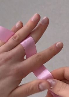 two hands holding pink ribbon in each other's palm, with one hand on the other