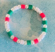 a close up of a bracelet with beads on a blue surface next to a pair of scissors