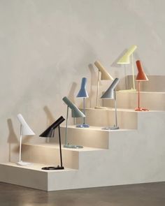 a bunch of lamps that are sitting on some steps in a room with concrete walls