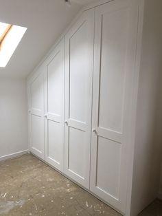 an empty room with white cupboards and a skylight