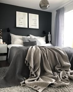 a bedroom with black walls and white bedding, two pictures on the wall above the bed