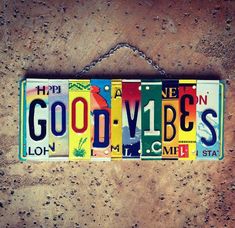 a license plate hanging on a wall with the words goodbye written in different colors and letters