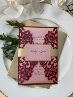 two wedding cards on a plate with flowers in the background