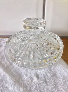 a clear glass bottle sitting on top of a white table cloth next to a wall