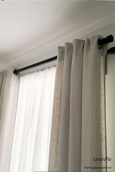 the curtains are hanging in front of the window with white drapes and black hardware