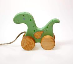 a green wooden toy horse with wheels on a white background and string attached to it