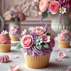 cupcakes decorated with pink and purple flowers on a table next to other cupcakes