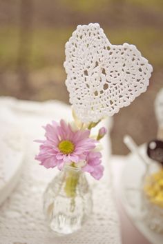 a small vase with flowers in it on a table next to other plates and cups