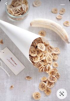 a banana peel and some dried bananas on a table with a white paper cone next to it