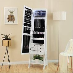 a white jewelry cabinet sitting on top of a hard wood floor next to a lamp