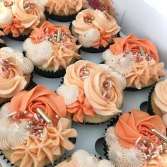 there are many cupcakes in the box with flowers on them and some pearls